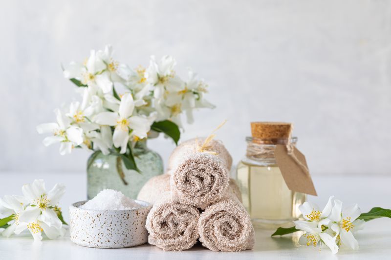 Spa concept of jasmine oil, with bath salt and flowers on a white background. Spa and wellness still life.